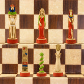 A chess set with pieces featuring ancient Egyptian motifs and figures, placed on a chess board.
This beautiful chess set depicts figures from the civilisation of Ancient Egypt, a society which began around
3150BC, growing rapidly along the  banks of the River Nile. Trade with other countries and its agricultural security helped it to become enormously prosperous; and due to this great wealth the rulers, known as Pharaohs, were very powerful, as were its priests.